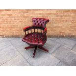 A RED LEATHER BUTTON UPHOLSTERED SWIVEL CHAIR on five prong wooden base