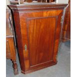 A MAHOGANY HANGING CORNER CUPBOARD the panelled door with brass key plate and hinges and opening