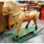 A HIDE-COVERED CARVED WOOD ROCKING HORSE with a horse hair mane and tail, and a leather saddle, on