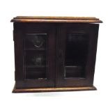 AN EDWARDIAN OAK SMOKERS COMPANION SET with hinged lid and pair of bevelled glass doors, the