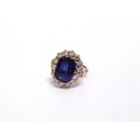 A SAPPHIRE AND DIAMOND CLUSTER RING the white mount unmarked, the rectangular cut stone, 13.6mm by