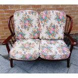 AN ERCOL STICKBACK TWO SEATER SOFA with floral covered cushions