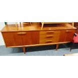 A TEAK SIDEBOARD fitted with three drawers flanked by drop-down cupboard and two door cupboard,