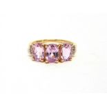 A 9 CARAT GOLD THREE STONE KUNZITE RING with four baguette diamonds to each shoulder, finger size O,