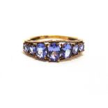 A SEVEN STONE TANZANITE 9 CARAT GOLD RING set with graduated oval cuts, finger size O, 2.2g gross.