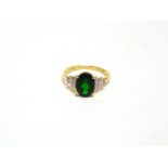 A TSAVORITE 9 CARAT GOLD RING the oval cut with stepped shoulders each shoulder set with three