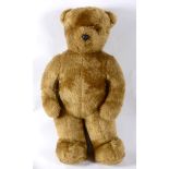 A LARGE FLOOR-STANDING GOLD FUR FABRIC TEDDY BEAR with orange plastic eyes and a black moulded