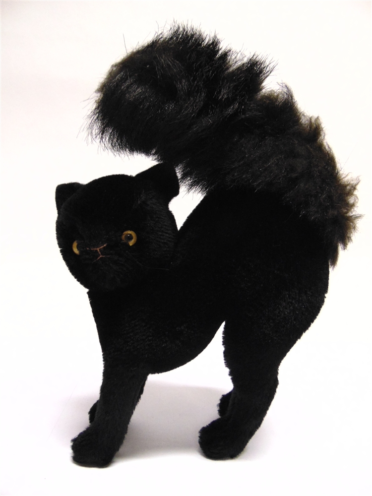 A BLACK MOHAIR PLUSH SOFT TOY CAT with a jointed head and yellow glass eyes, 21cm long.