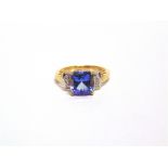 A 9 CARAT GOLD TANZANITE AND DIAMOND RING the cushion cut stone flanked by a trio of single cuts