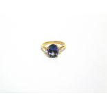 A 9 CARAT GOLD BICOLOUR TANZANITE RING the oval cut stone with a small brilliant cut to each