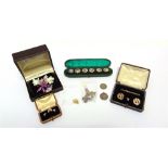 A CASED SET OF FIVE ROCOCO STYLE BUTTONS with a single Arts and Crafts button taking the sixth