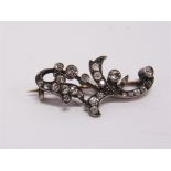 A LATE VICTORIAN DIAMOND BROOCH of foliate scroll design, set with old brilliants and rose cuts, 3cm