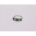 A DIAMOND AND EMERALD FIVE STONE RING set with three graduated step cut emeralds, and two old