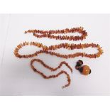 THREE AMBER NECKLACES with tumbled beads; with a large amber bead pendant with metal mounts; 157g