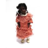 A BLACK BISQUE SOCKET HEAD DOLL with a black wig, fixed brown glass eyes, pierced ears, and an