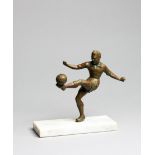 A small spelter figure of a footballer, bronze patina, modelled volleying the ball,