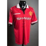 A red Manchester United replica jersey signed by the 'holy trinity' George Best,