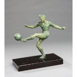 A spelter figure of a footballer, verdigris patina, modelled striking a left-foot volley,