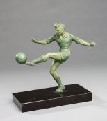 A spelter figure of a footballer, verdigris patina, modelled striking a left-foot volley,