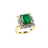 Yellow gold emerald and diamond cluster ring, tests 18 ct. The emerald cut emerald weighing approx.