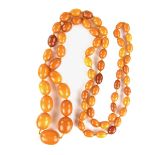Graduated amber bead necklace. Comprising sixty-five ovoid butterscotch amber beads. Length 1220 mm.
