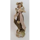 A Royal Dux pottery female figure the figure dressed in frilly hat, frilled pierced shoulder cuffs