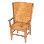 An oak Orkney armchair the curved straw-work back joined to scroll arms above a straw woven drop-