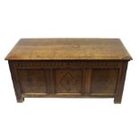 An oak coffer the hinged top above a fluted frieze and triple panel front carved with diamond
