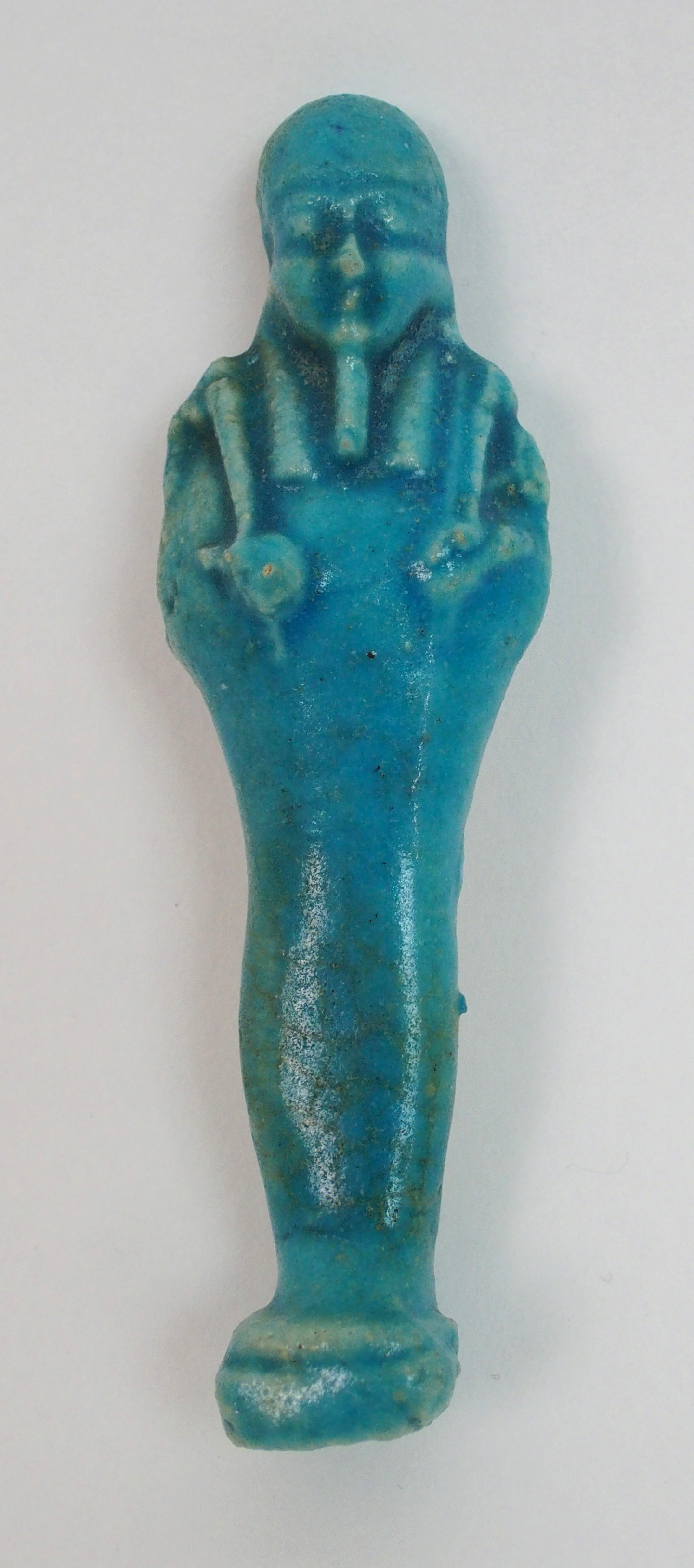 An Egyptian blue glazed ushabti figure holding fly whisks, unnamed, 10cm high