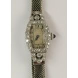 A platinum and diamond cocktail watch with pretty flower motif to shoulders, cream dial with black