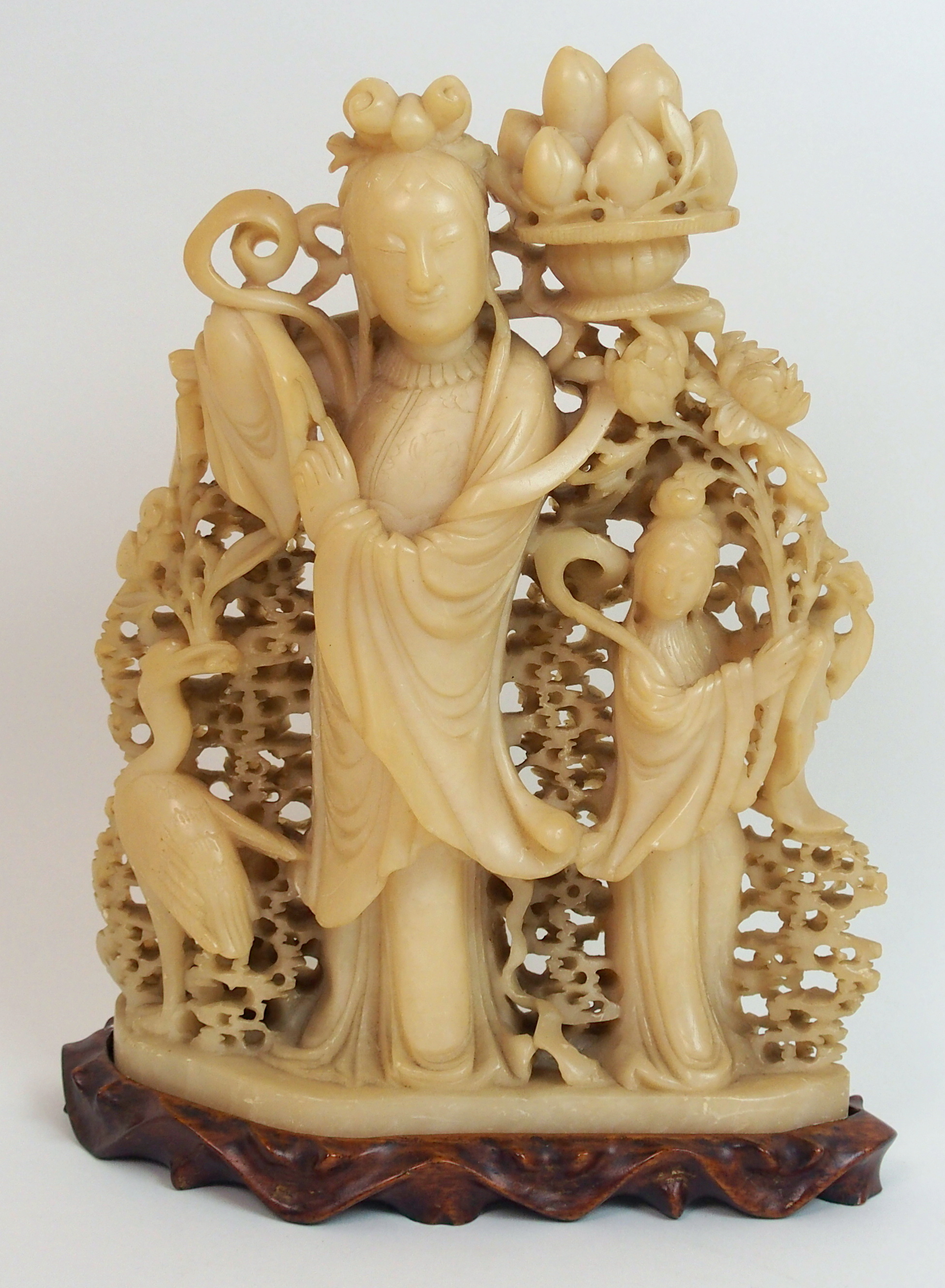 A Chinese soapstone carving of Guanyin standing with peaches, beside attendant and stork