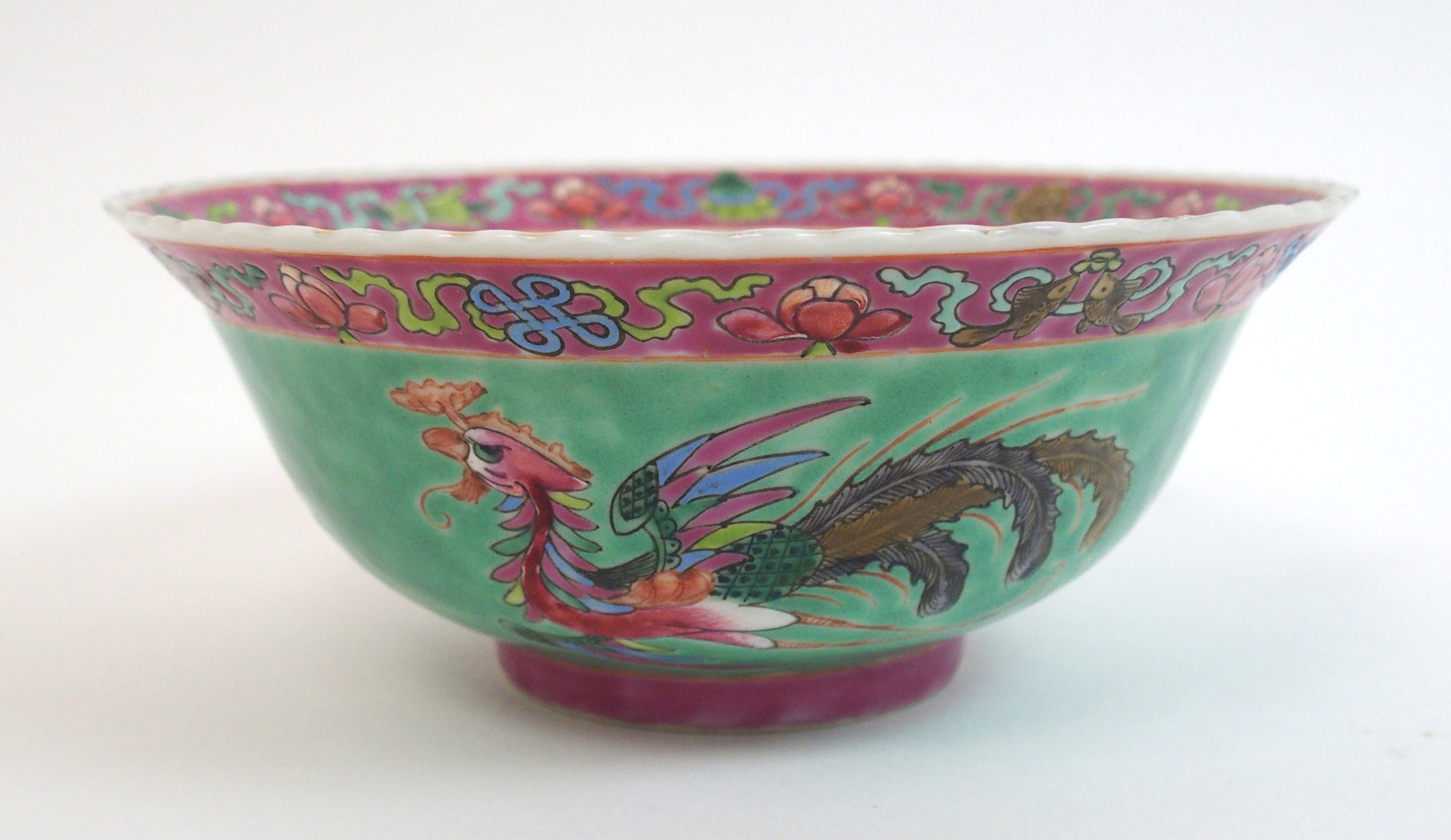 A Chinese bowl painted with an exotic bird, rockwork and chrysanthemum on a green ground, printed