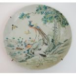 A Chinese dish painted with a peacock, herons and ducks beneath trees and beside a lake, (minor