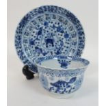 A Chinese blue and white tea bowl and saucer painted with fish surrounding a crab amongst foliage,