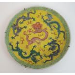 A Chinese yellow ground dish painted with four green dragons surrounding a red dragon within a