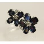 An 18ct white gold sapphire and diamond flower ring set with oval mixed cut sapphires and