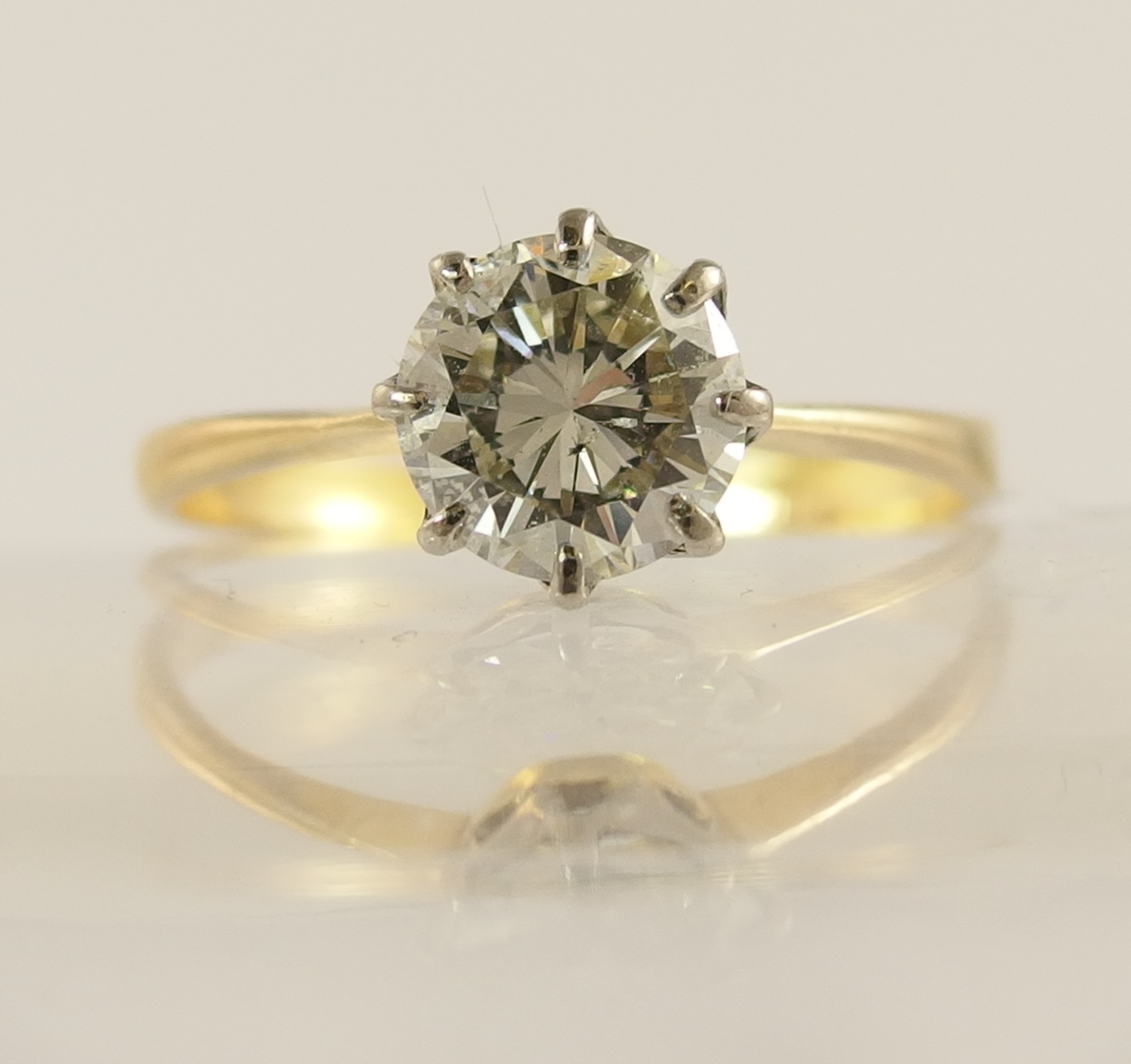A 1.12ct diamond solitaire ring with classic crown mount in white metal with a tapered yellow