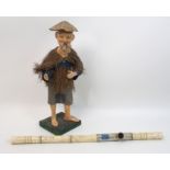 A Chinese papier mache figure of a worker with straw cape and linen costume, 37cm high and a