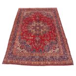 A red ground Sarouk rug with traditional medallion design, 350 x 245cm