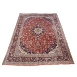 A red ground Keshan rug with central medallion and a blue border, 395 x 300cm