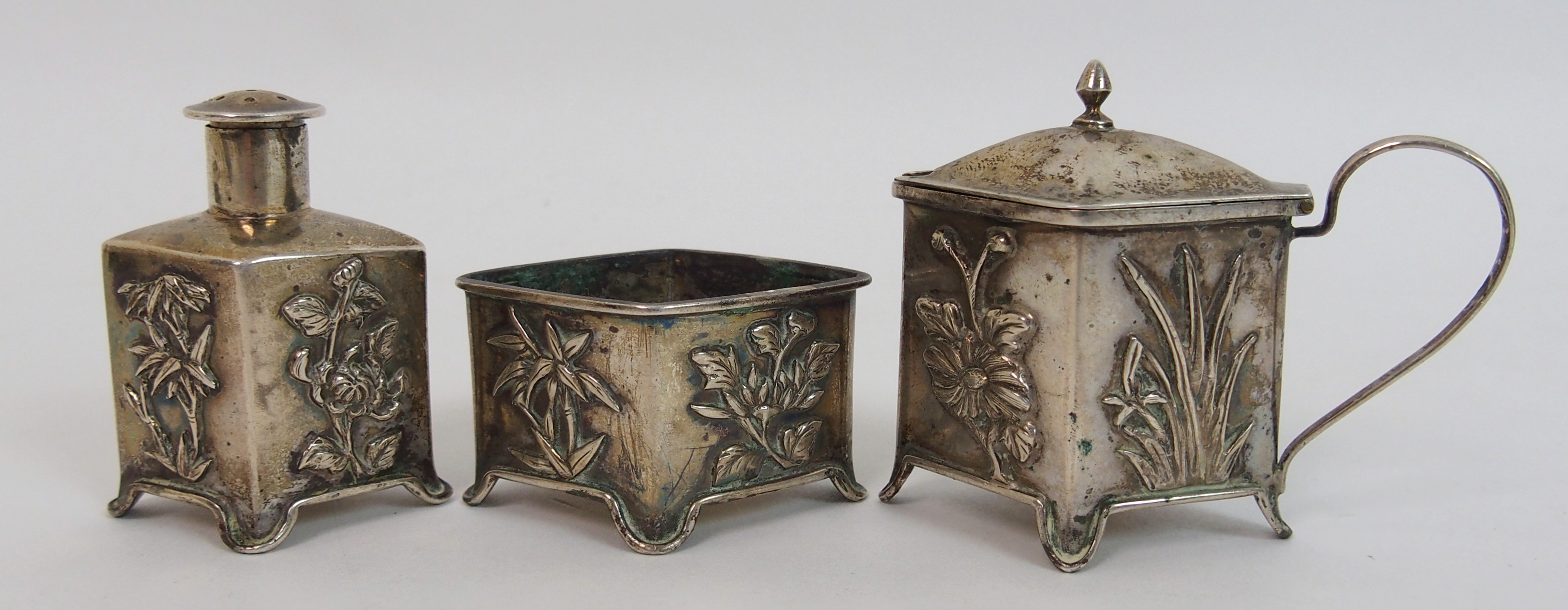 A Chinese silver cruet set cast with foliage comprising; salt cellar, pepper pot and mustard pot (