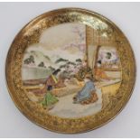 A Satsuma saucer dish painted with a nobleman and family on a pavilion in a garden within blue
