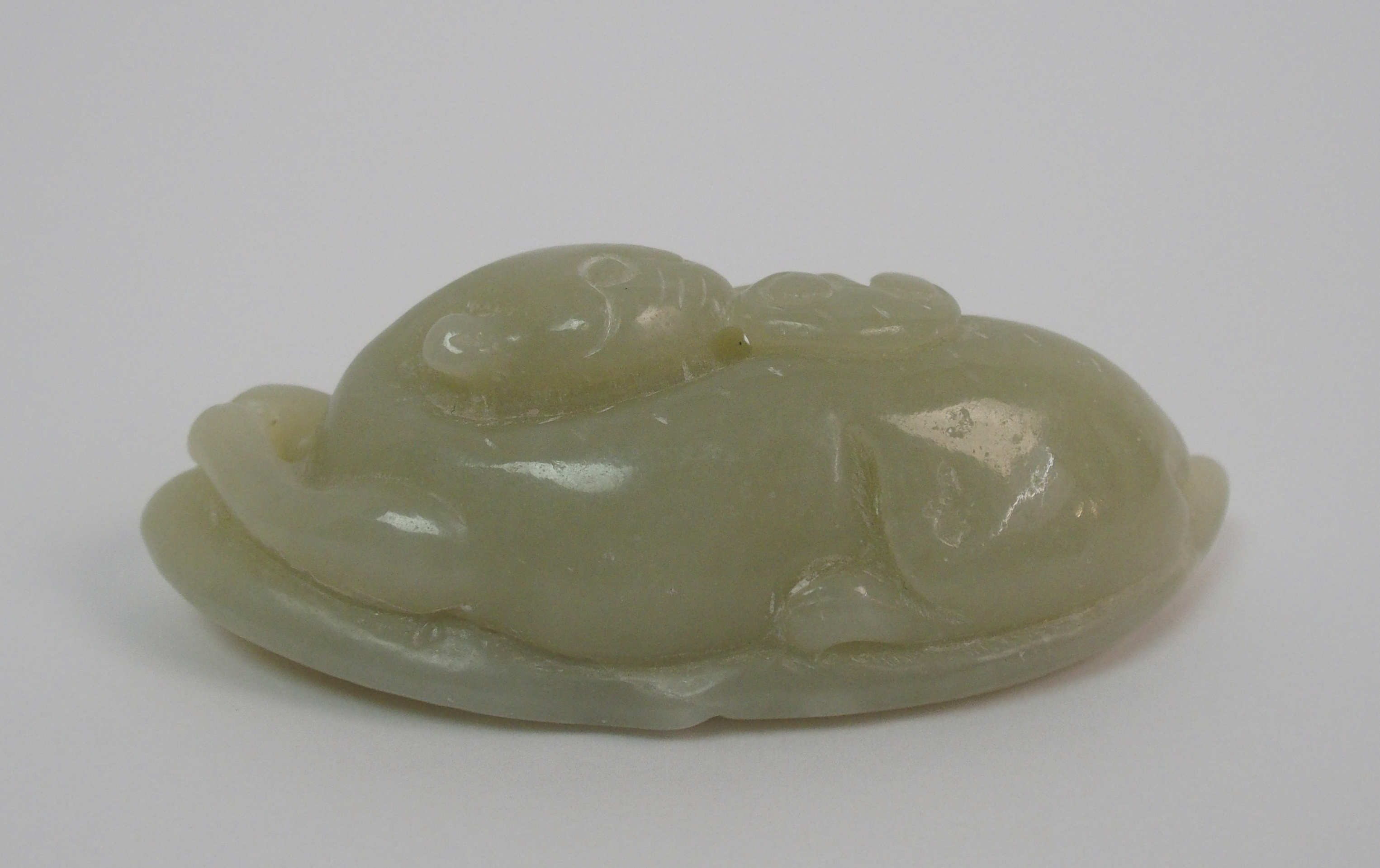 A Chinese hardstone carving of a feline recumbent with scroll in mouth and resting on a leaf, 7. - Image 5 of 10