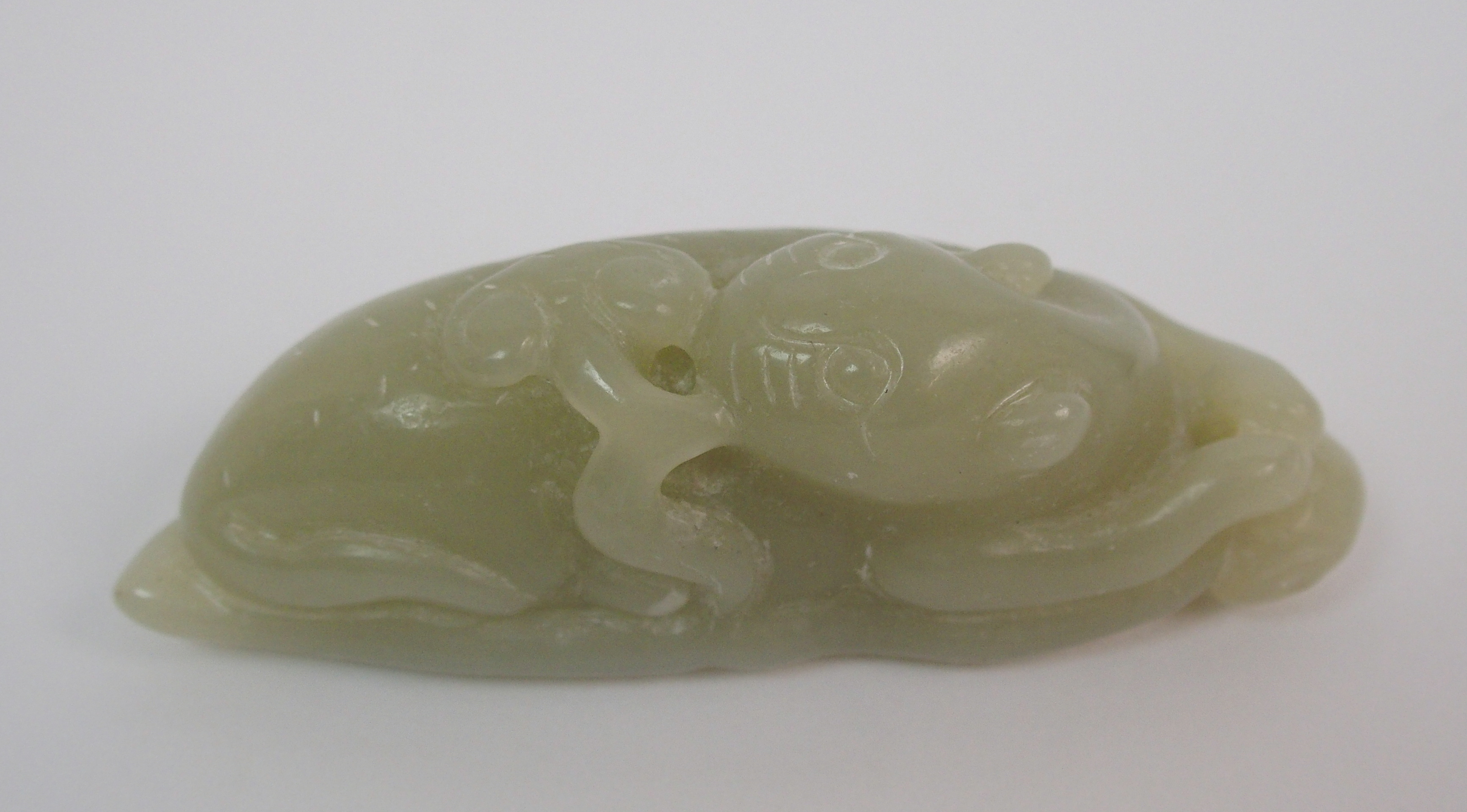 A Chinese hardstone carving of a feline recumbent with scroll in mouth and resting on a leaf, 7.