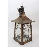 An Arts and Crafts brass hall lantern of pagoda form with textured glass panels covered by wire