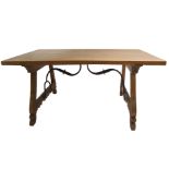 A Spanish walnut trestle table the rectangular single plank top on scroll carved legs joined by