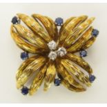 A 14ct gold sapphire and diamond brooch of stylised flower form, the three diamonds add up to an