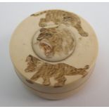A Japanese ivory box carved with two prowling tigers and a tiger head medallion, 6.5cm diameter