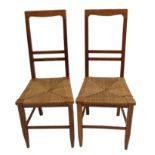 A pair of Arts and Crafts chairs in the style of E. A. Taylor with rush seats beneath horizontal