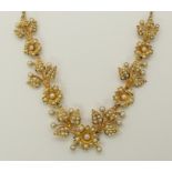 A 15ct gold pearl set flower necklace stamped 15ct to one of the leaves, the pearl set section